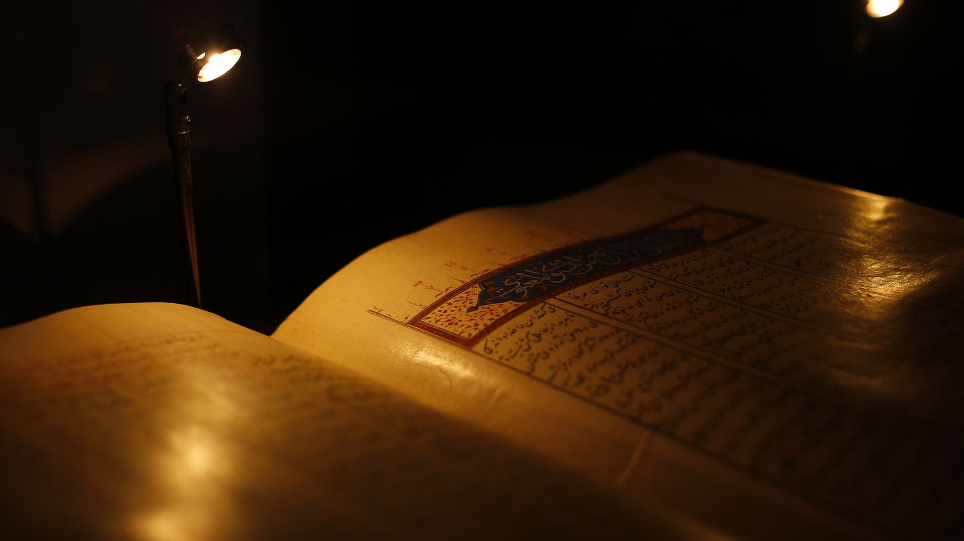 Close-up of an ancient illuminated manuscript with ornate script and warm golden light